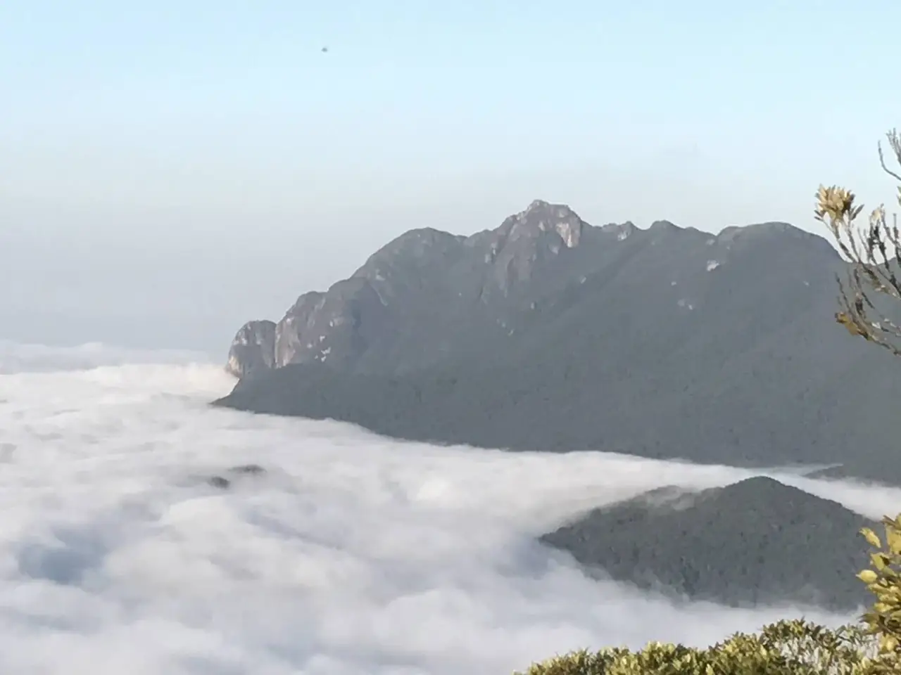 Pico rochoso acima de um mar de nuvens